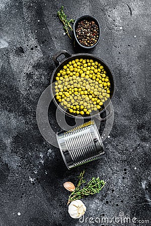 Green peas in a cast-iron bowl. Canned food. Black background. Top view Stock Photo