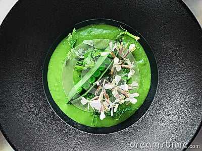 Green peas soup with roquette flowers Stock Photo