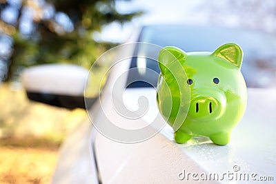 Green piggy bank money box on top of car hood, new vehicle purchase, insurance or driving and motoring cost Stock Photo