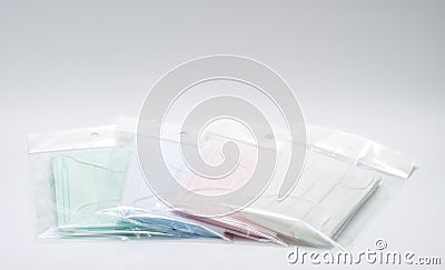 Green, pink, light blue and white ear loop disposable face mask in plastic bag overlapping, used for covering mouth and nose. It p Stock Photo