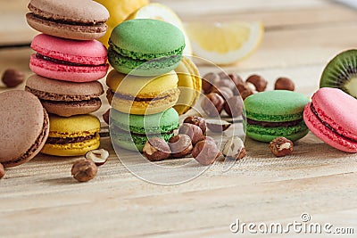 Green, pink, yellow and brown french macarons with lemon, kiwi and hazelnuts Stock Photo