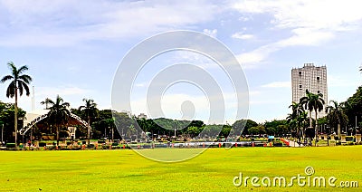 Green plains of the historic Luneta park capturing the famous photo bomber building Stock Photo