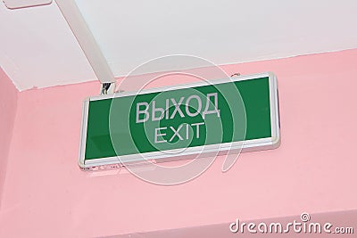 Green plate with the inscription exit in English and Russian on a pink wall Stock Photo