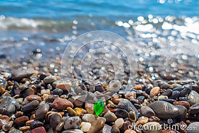 Green polished glass pebble on seashore Stock Photo