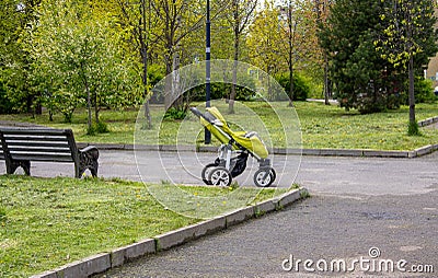 A green pram stands in the middle of the street. Travel with a child, transportation of a child, concepts of a child's walk Stock Photo