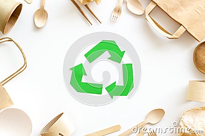 Green recycling sign with waste materials paper, bag, cup, wooden flatware on white background top view Stock Photo