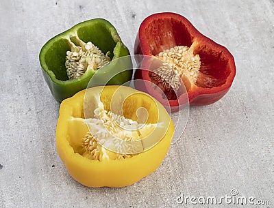 Green, red and yellow bell pepper halves over rustic background Stock Photo