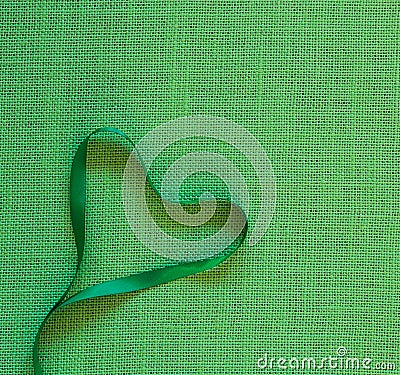 Green Ribbon Heart on Burlap Linen Background with copy space. It`s square with a trendy flat layout Stock Photo