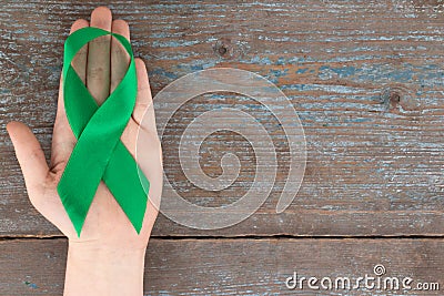 Green ribbon. Scoliosis, Mental health and other, awareness symbo on the wooden background with copy space Stock Photo