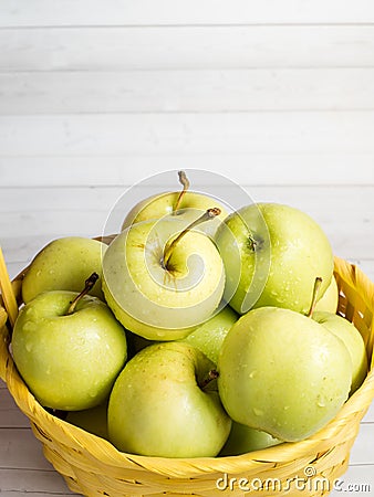 Green ripe apples in a wicker yellow basket Stock Photo