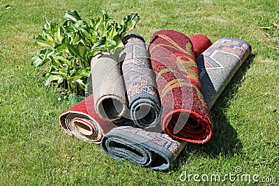 On a green rural grass dirty synthetic old house carpets lie Stock Photo