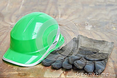 Green safety helmet and gauntlet cloves on a woode background Stock Photo