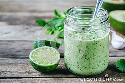 Green salad dressing with avocado, lime and cilantro in a glass jar Stock Photo