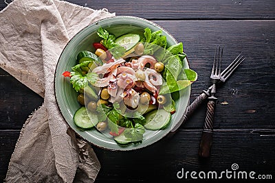 Green salad with octopus tentacles, boiled potatoes, cucumbers, sweet peppers, olives and parsley. Sea food. Top view Stock Photo