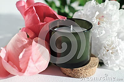 green scented candle and peony flowers. home fragrances for relaxation and calm. flower fragrance for home. unbranded Stock Photo