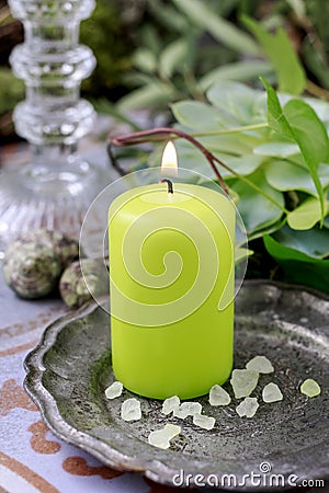 Green scented candle on silver plate Stock Photo