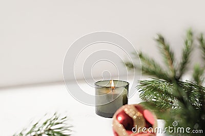 green scented christmas candle next to pine branch and red christmas ball. copy space. holiday home decor. forest and Stock Photo