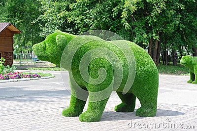 Green sculpture in the shape of a bear in the city park. Selective Focus Stock Photo