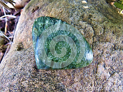 Green seraphinite crystal stone cabochon with angel wings pattern on a rock Stock Photo