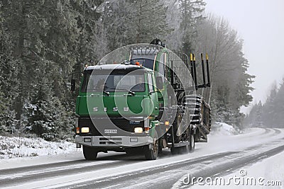 Green Sisu SM300 Truck Hauls Forestry Equipment in Winter Editorial Stock Photo