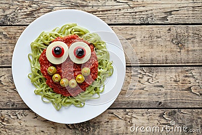 Green spaghetti pasta creative halloween food monster with cute smile and big mozzarella eyeballs Stock Photo