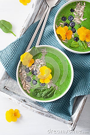 Green spinach smoothie bowl with blueberry, chia seed and edible pansy flowers Stock Photo