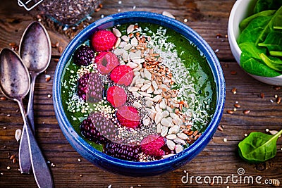 Green spinach smoothie bowl with raspberry,blackberry,flax seeds, sunflower seeds and coconut chips Stock Photo