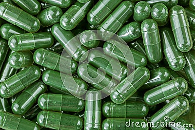 Green Spirulina powder, blue-green algae in clear capsules Stock Photo