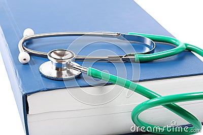 Green stethoscope lying on a big blue book isolated on white background Stock Photo