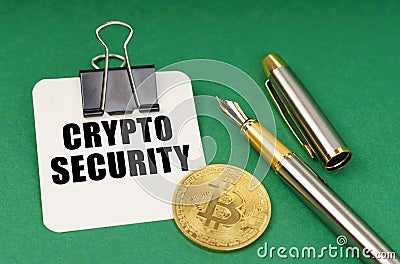 On a green surface, a bitcoin coin, a pen and a sheet of paper with the inscription - Crypto security Stock Photo