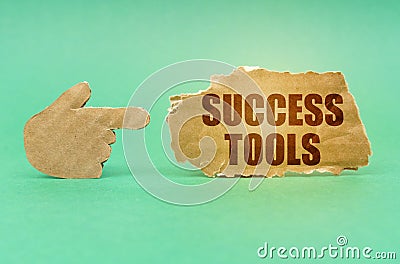 On a green surface, a cardboard hand points to a sign with the inscription - Success Tools Stock Photo