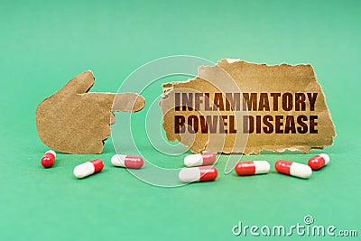 On the green surface of the tablet and a hand pointing to a sign with the inscription - Inflammatory Bowel Disease Stock Photo
