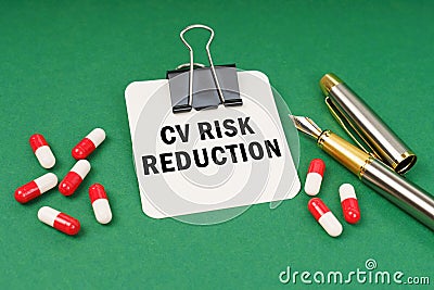 On the green surface of the tablet, a pen and a notepad with the inscription - CV Risk Reduction Stock Photo
