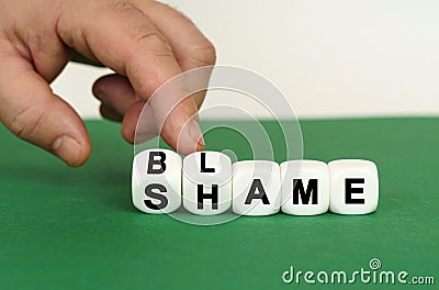 On a green surface are white cubes with the inscription - BLAME or SHAME Stock Photo