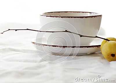 Green tea with japanese quince on white linen textile, minimalist composition with herbal tea in white cup with fruit branch Stock Photo