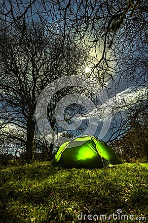 Green tent surrounded by trees under the full moon in Blessington Lakes, Wicklow, Ireland Stock Photo