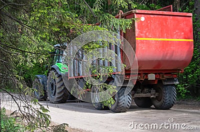 Green tractor carries a red trailer Stock Photo