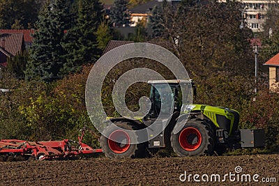 Green tractor plough brown autumn field near Steti town Editorial Stock Photo