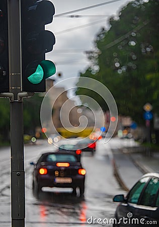 Green traffic light during the rain, Cars drive by Stock Photo