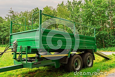 Green trailer in a field with ramp down by a forest. Concept heavy machinery delivery Stock Photo