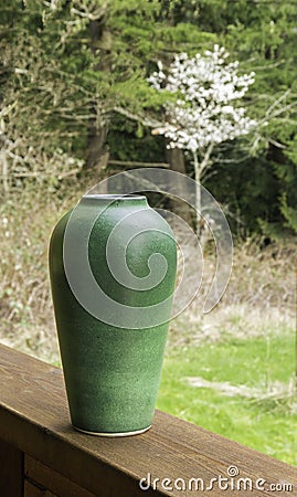 Green Vase Outdoors with Blooming Cherry Tree and Forest Stock Photo