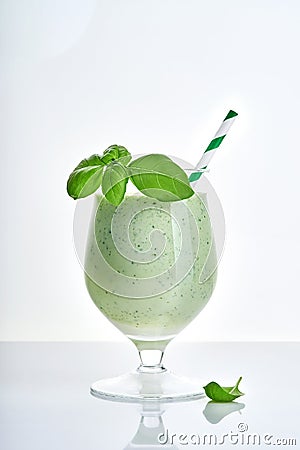 Green vegetable juice or smoothie garnished with leaf of fresh basil in coctail margarita glass isolated on white Stock Photo