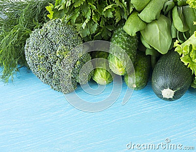 Green vegetables on a blue wooden background. Parsley, spinach, cucumber, broccoli, dill and zucchini. Top view. Green vegetables Stock Photo