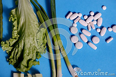 Green vegetables versus vitamins on sky blue background Stock Photo