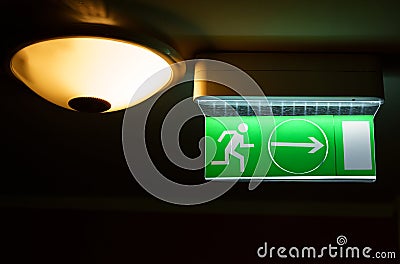 A green warning light board depicting a running man with an arrow. Evacuation sign. Stock Photo