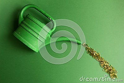 Green watering can with beads on the green blackground Stock Photo