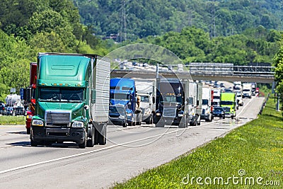 Green 18-Wheeler Leads Heavy Highway Traffic Stock Photo