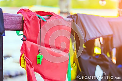 A green whistle with red life jacket hanging on the railing around the walkway for safely of passengers Stock Photo