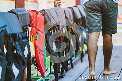 A green whistle with red life jacket hanging on the railing around the walkway for safely of passengers Stock Photo