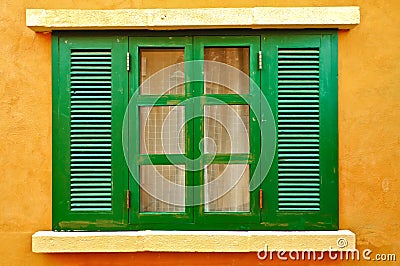 Green window on yellow wall Stock Photo